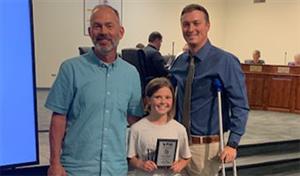 Image of teacher, student and principal with award